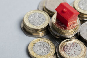 Money piled up with a monopoly house demonstrating costs of a garage conversion