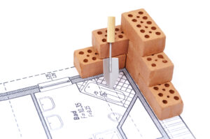 Bricks next to some home building plans representing a garage conversion